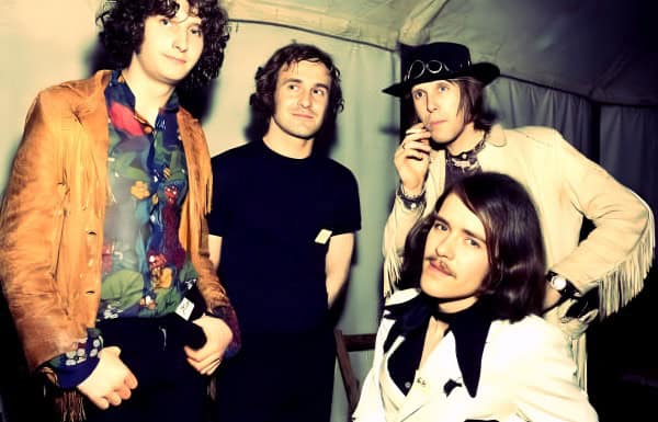 Past daily archive music band photo, vintage rock band members, retro style, 1970s music scene, iconic music history, classic rock look, musicians in a tent setting.