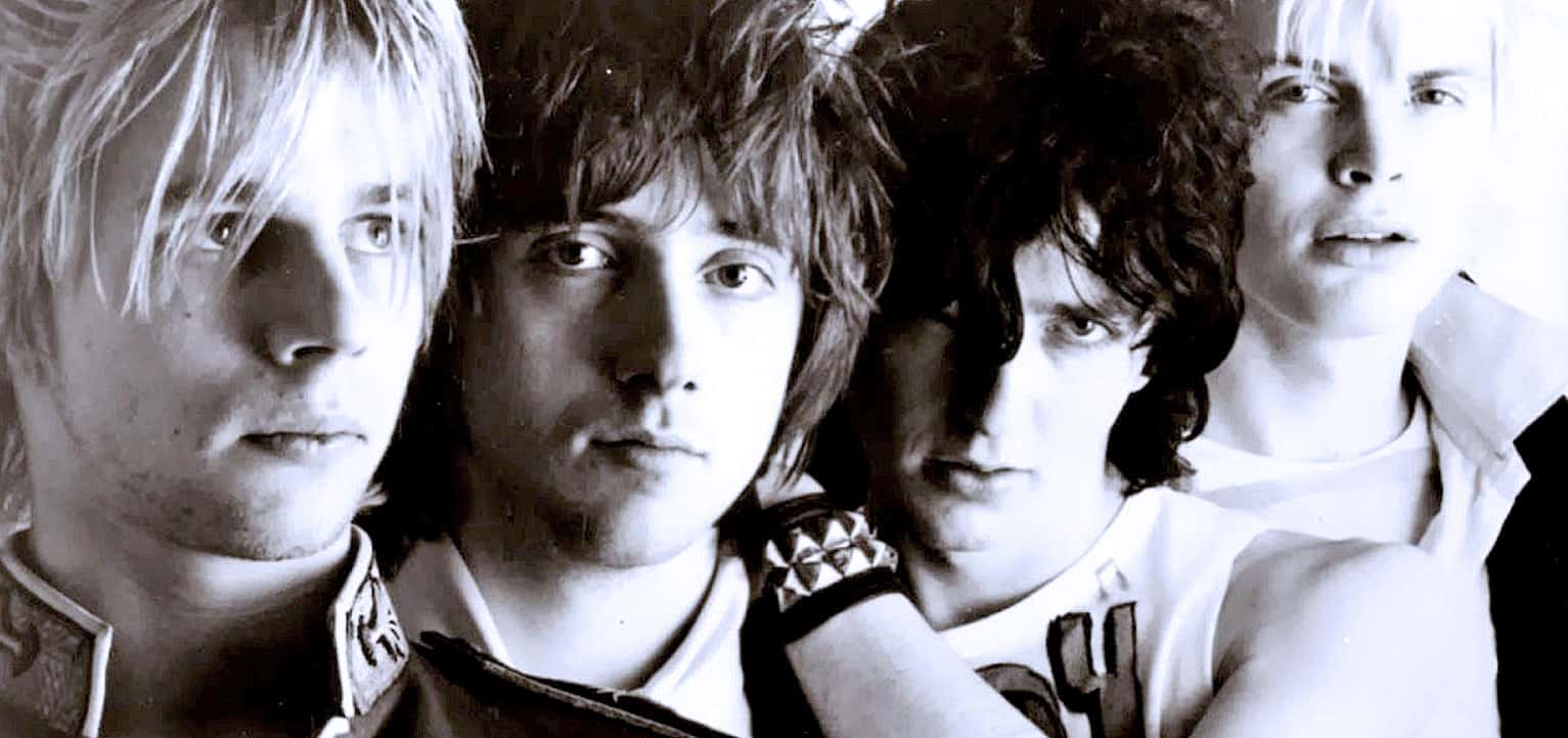 A black and white close-up photo of the iconic British rock band, T. Rex, featuring members with distinctive hairstyles and edgy fashion, capturing their vintage style and influence in music history.