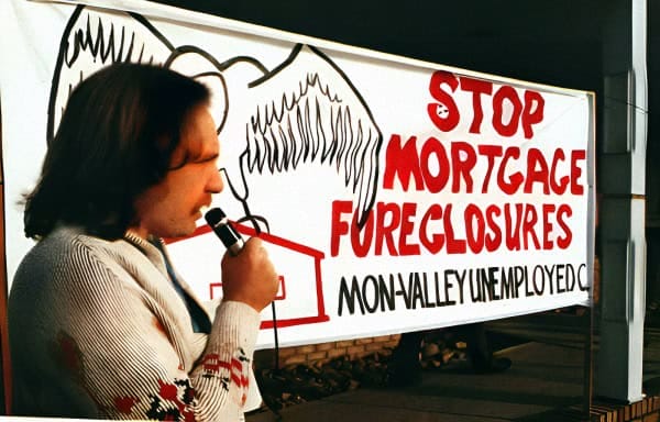 Stop mortgage foreclosures protest banner at Mon Valley Unemployed Committee rally, advocating against home repossession and economic hardship, highlighting mortgage crisis issues.