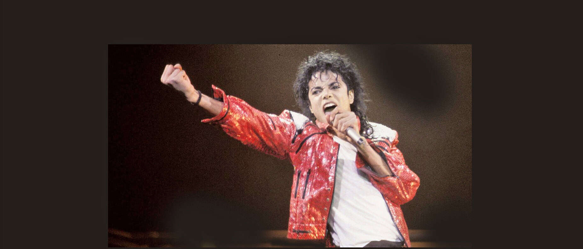 Performance of Michael Jackson singing on stage with iconic red jacket, capturing music history, live concert, legendary artist, pop music icon, classic music performance, vintage concert photo, music archive, historic performance, musical entertainment,.