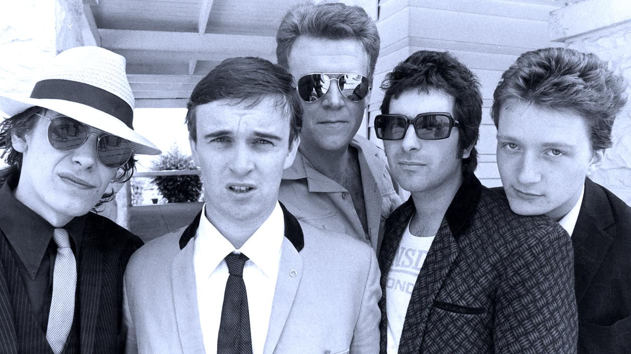 Men wearing sunglasses in black and white photo, 1980s vintage style band, casual fashion, rock music culture, group portrait, retro aesthetic, music history image, iconic music scene.