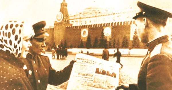 Vintage Soviet soldiers reading a newspaper near the Kremlin, capturing historical news and wartime imagery.