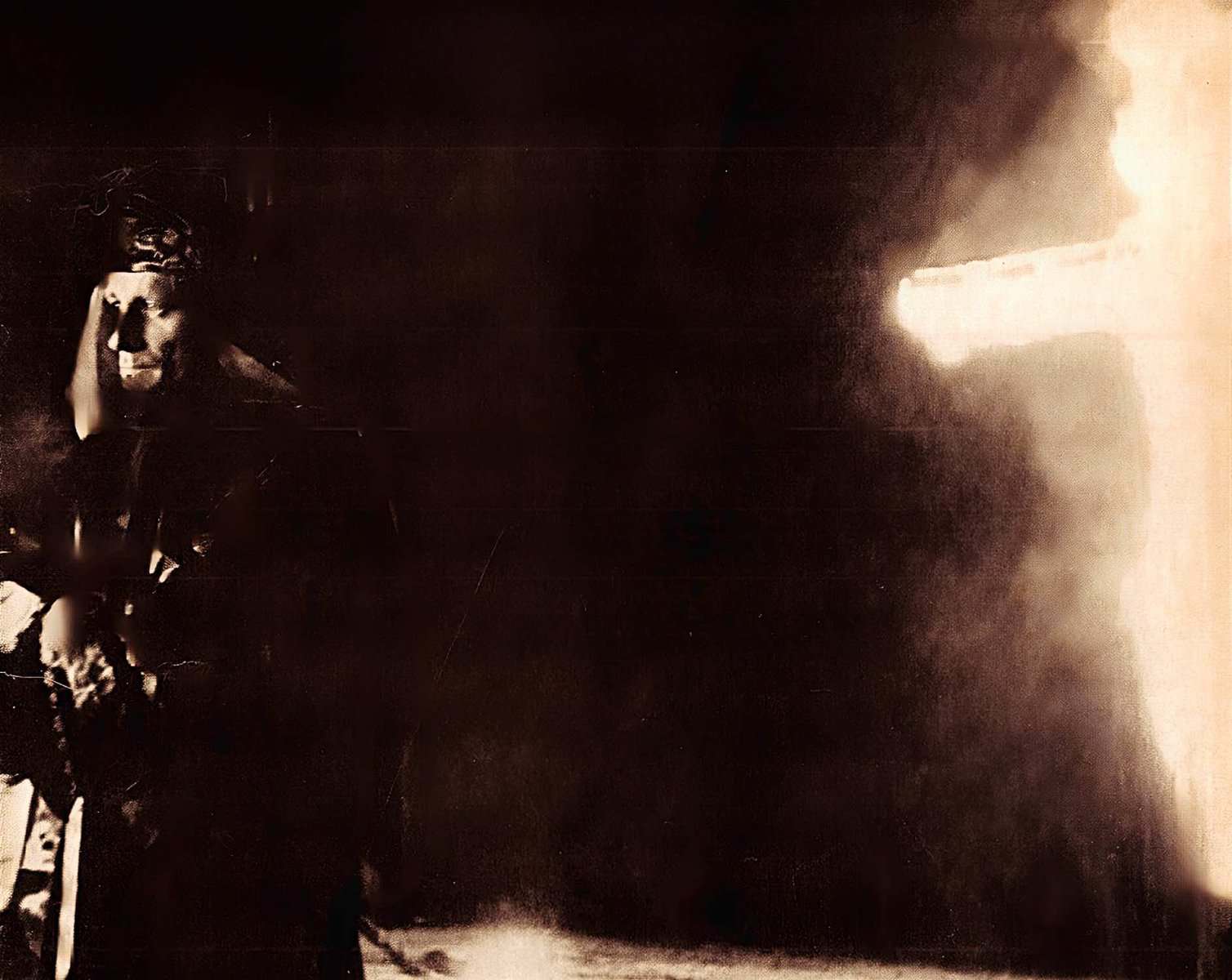 A vintage black-and-white photo of a woman with floral accessories on her head and a dark dress, possibly a performer or historical figure, with a bright light or fire in the background, evoking nostalgia and historical significance.