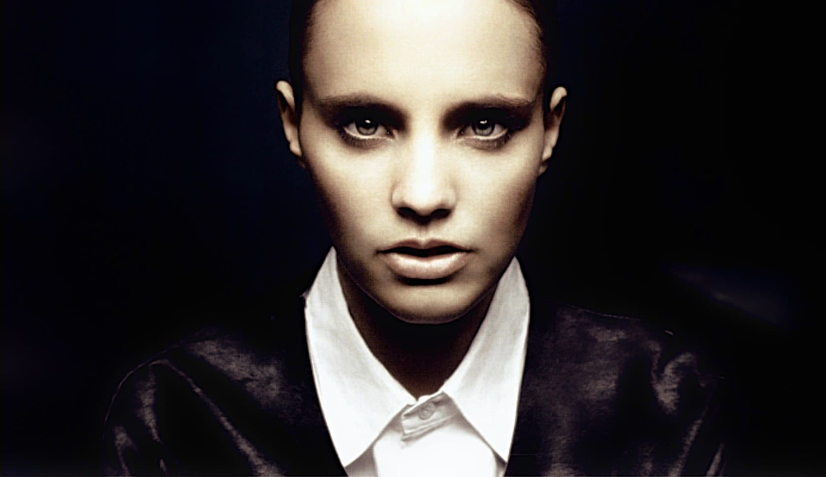 Bold black-and-white portrait of a woman with slicked-back hair and intense gaze, showcasing iconic fashion and style from music and news history archives.
