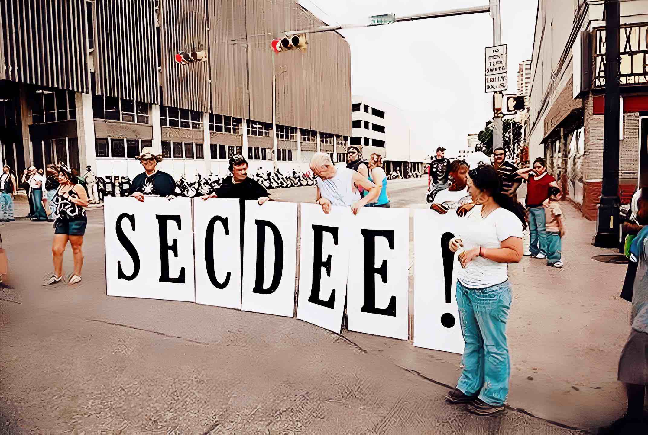 Protesters on city street holding large signs spelling "SECEDE" during a political demonstration, capturing a moment of activism and community engagement.