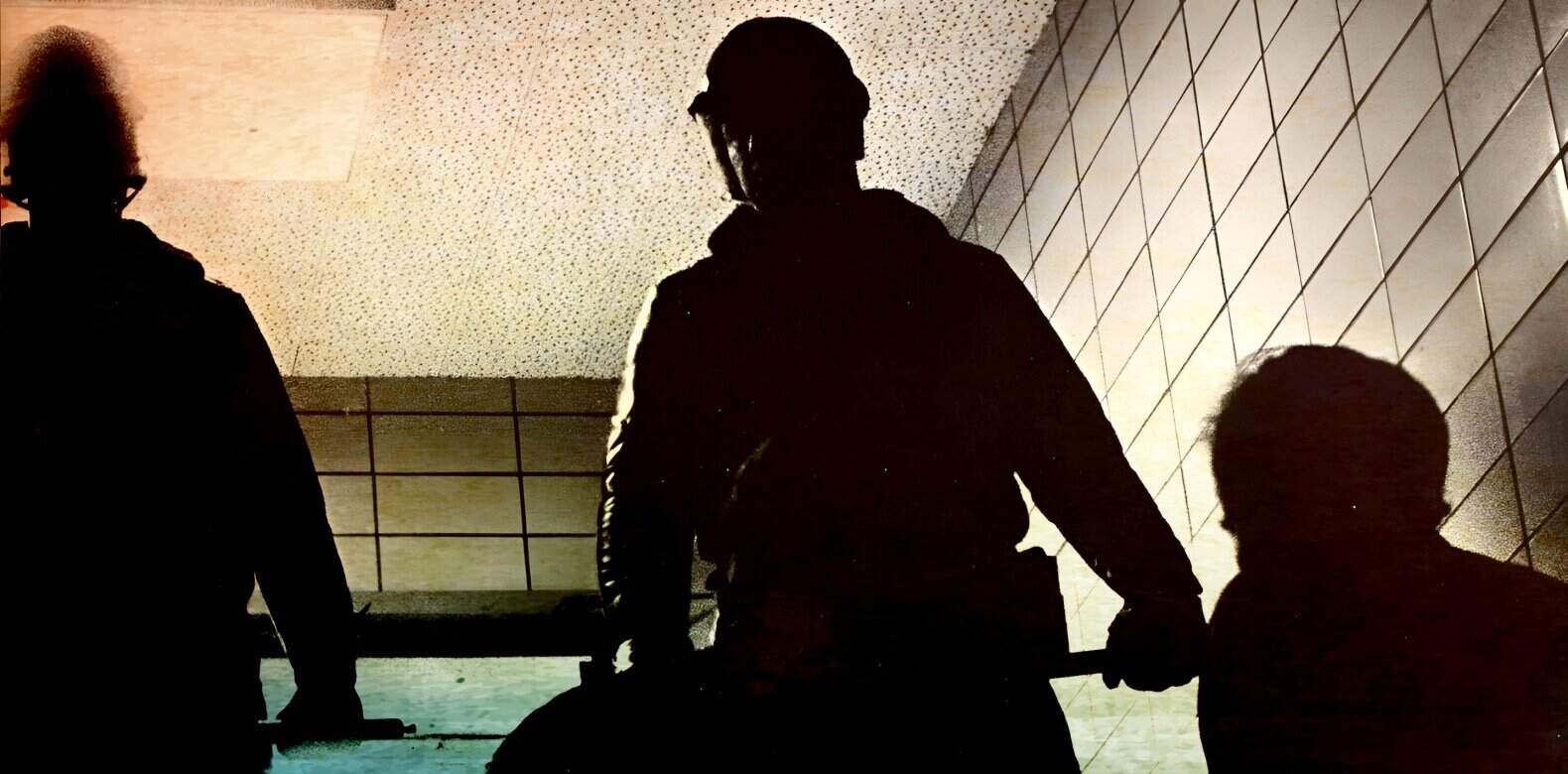 Silhouette of people with skateboards in an indoor skatepark, urban recreational scene, youth skateboarding, sports and activity, skateboarding culture and lifestyle, modern skatepark environment, street sports imagery.
