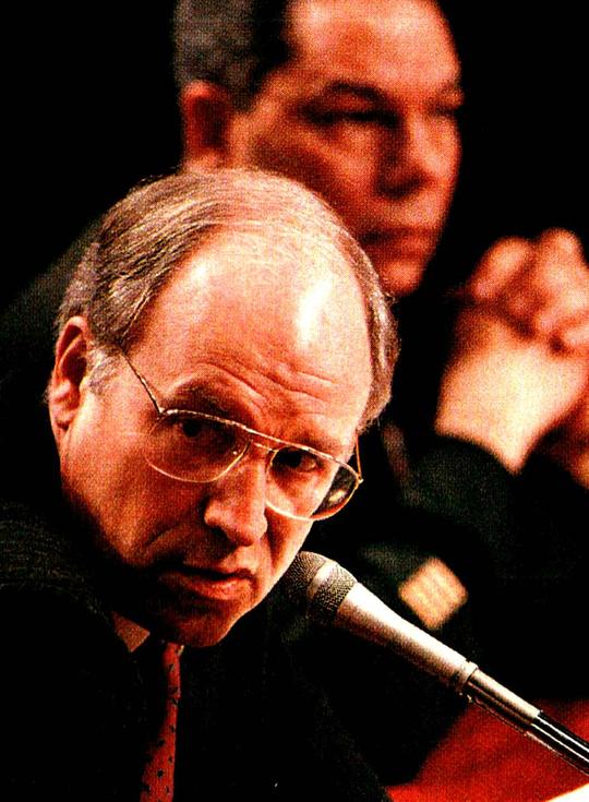 John Kerry speaking at a press conference with a microphone in front of him, with other officials in the background. Focus on political news, history, and important moments captured in the sound archive.