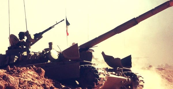 Destroyed military tank in a desert landscape with dust and smoke, representing war and conflict.