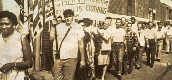 Protesters marching in a historic civil rights demonstration, holding signs advocating for fair clothing labor standards.