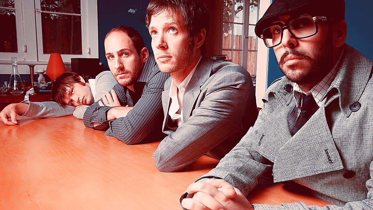 Regretful men sitting at a conference table with music room background, old-fashioned style, serious mood, retro fashion, film-like quality, emotional expression, indoor setting.