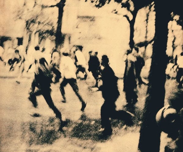 People dancing outdoors in a historical black-and-white photograph, capturing a lively moment of community and culture from past news and history archives.