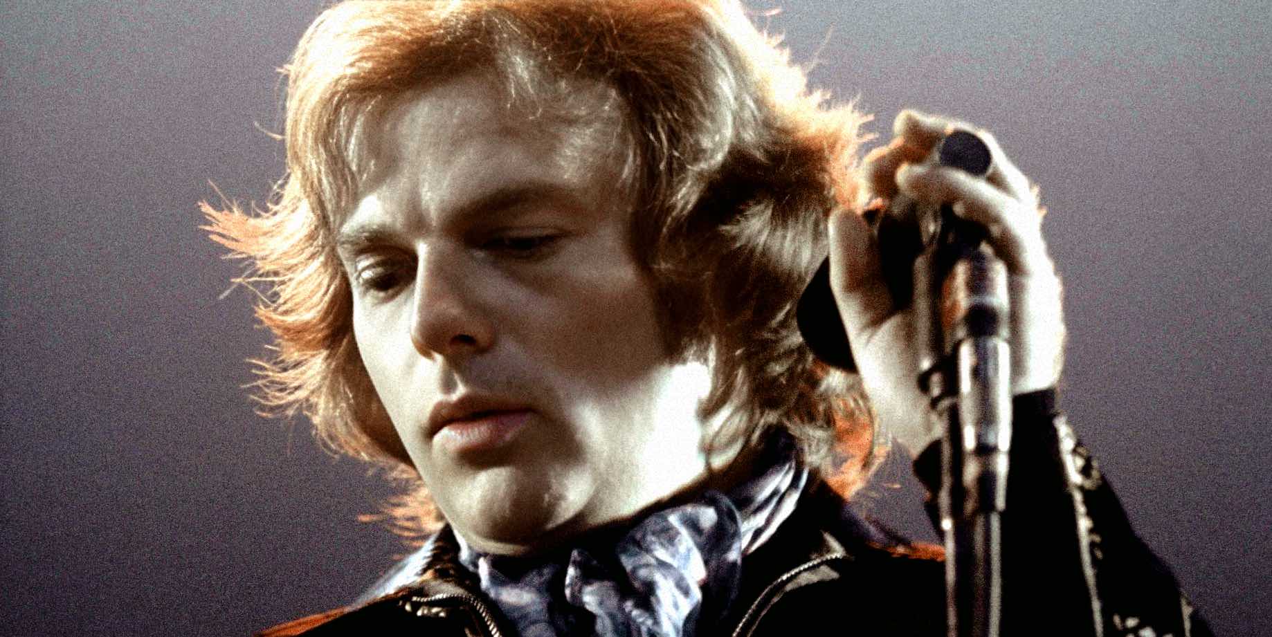 Vintage rock singer performing on stage with microphone, iconic image of music history.