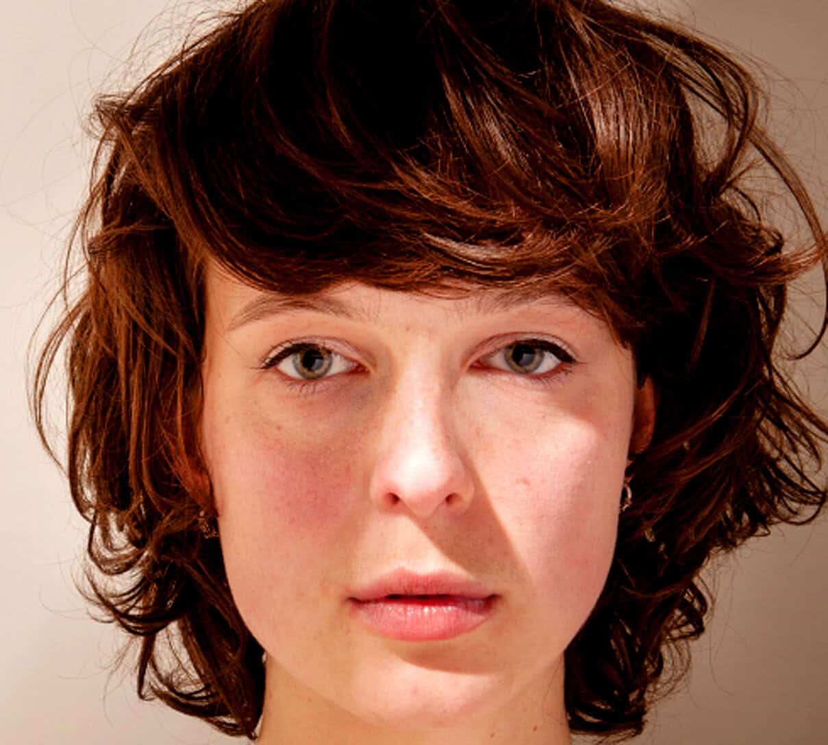 Young woman with short, curly red hair and fair complexion, showcasing a natural and authentic portrait for fashion or beauty SEO images.