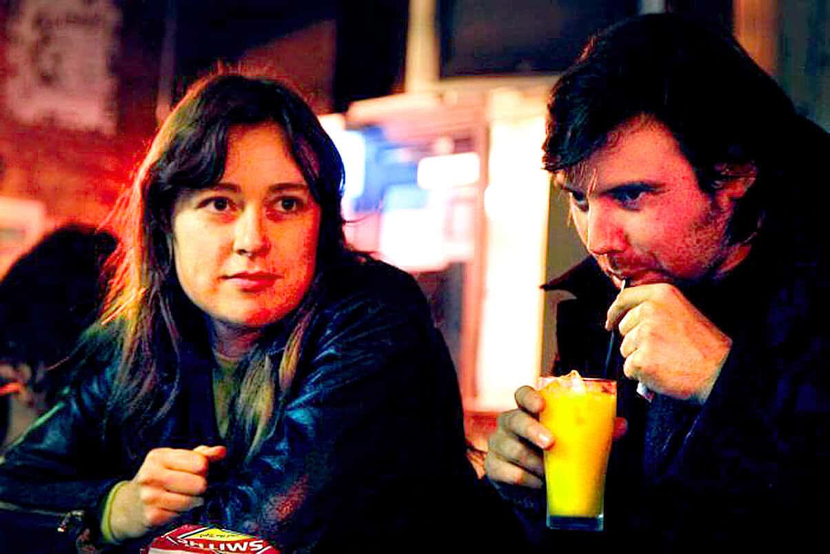 Famous scene from the movie "High Fidelity" featuring John Cusack and Iben Hjejle sitting in a bar, capturing a moment of music and entertainment.