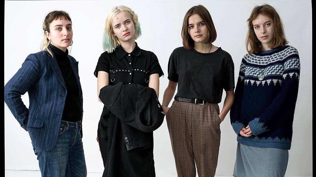 Girl band featuring four women with casual and vintage-inspired clothing, posing against a plain background.