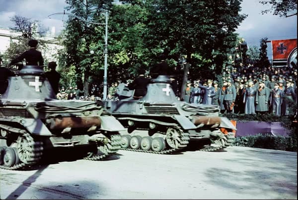 M1 Abrams tanks participating in a historical military parade with soldiers and a Red Cross flag, showcasing profound moments in wartime history.