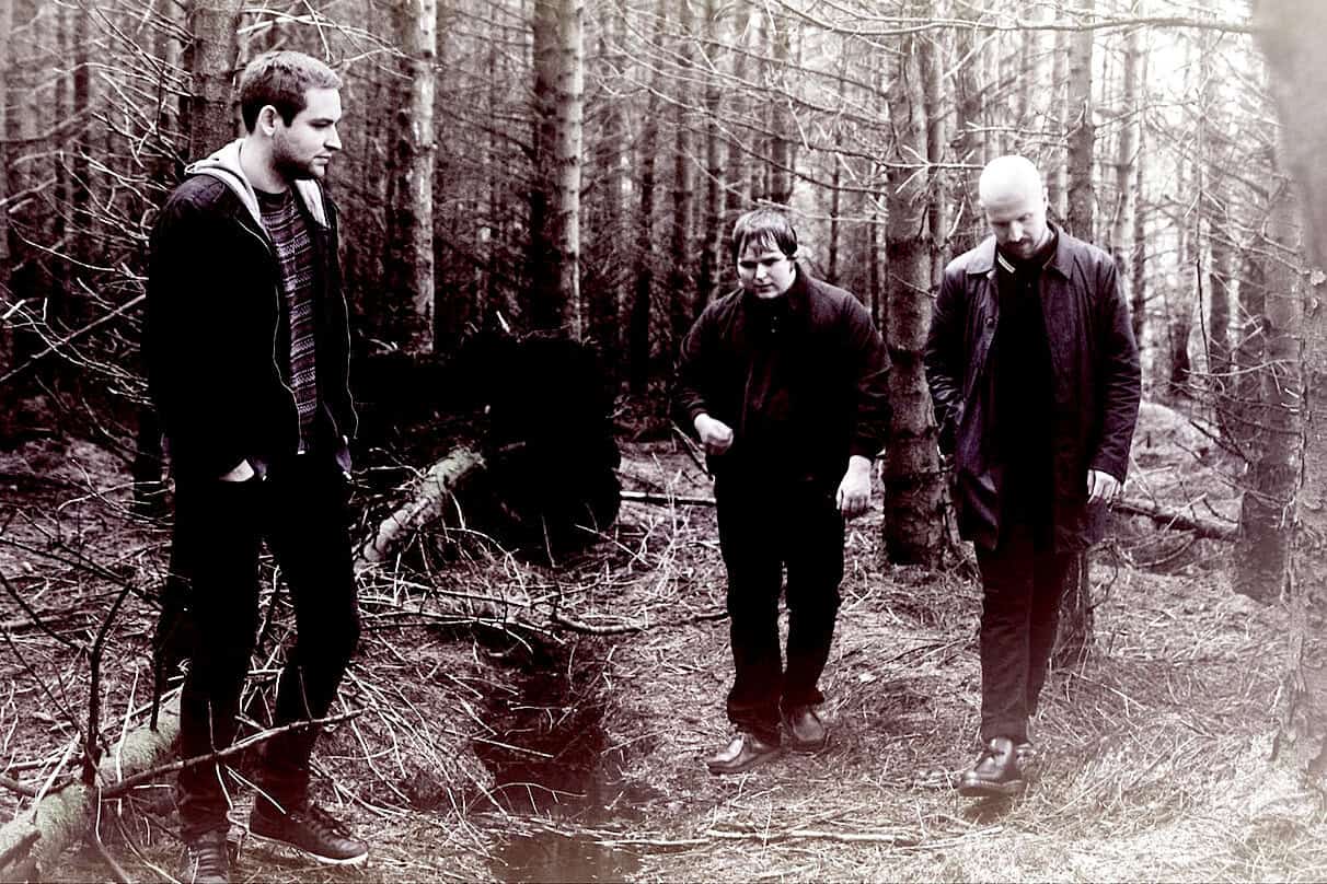 A forest scene with three men walking through a wooded area, capturing natural sounds and environmental ambiance. Perfect for sound archive content related to nature, outdoor recordings, and environmental history.