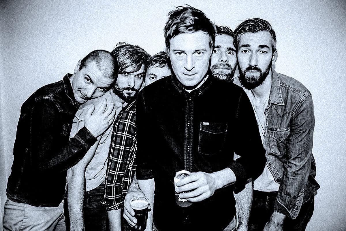 A black and white photo of a five-member band with a vintage rock vibe, highlighting music history and archival sound recordings.