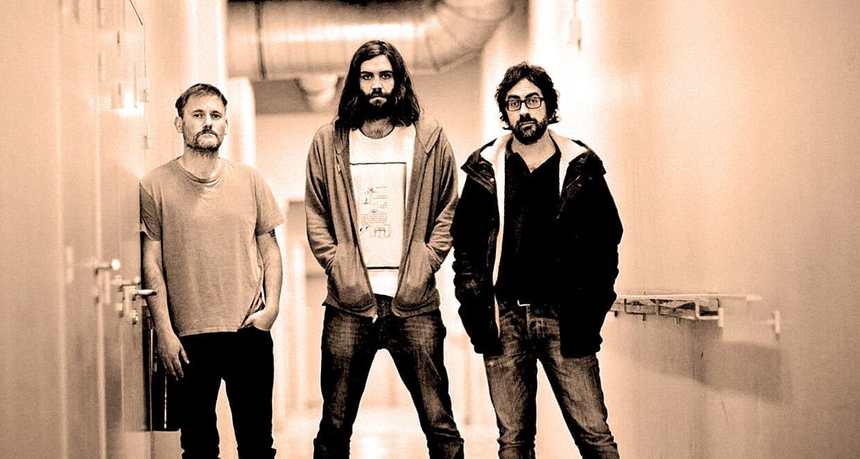 A band of three men standing in a hallway, representing music and podcast recordings on Past Daily, a sound archive of news, history, and music, emphasizing vintage sound preservation and historical audio archives.