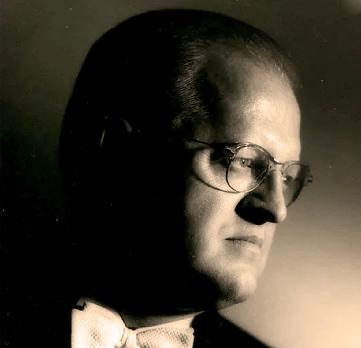 Silhouette of a man with glasses and bow tie, vintage black and white portrait, historic figure, classic style, timeless news and music archive, Past Daily.