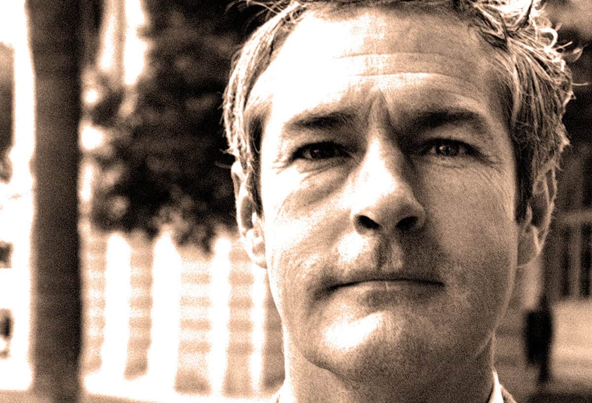 Serious man with serious expression, outdoor background, black and white, vintage photo emphasizing history and timelessness of past events.