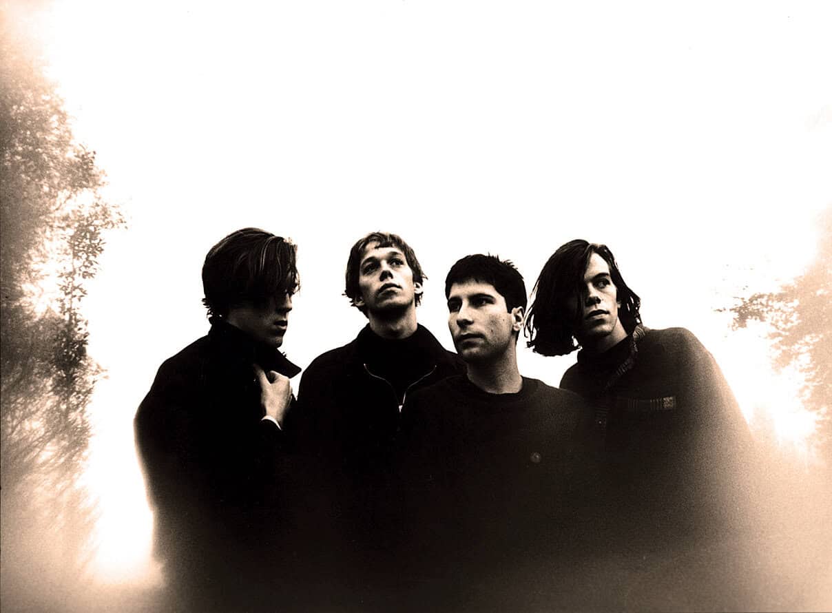 California-based alternative rock band in black and white outdoor photo, members looking in different directions, captured at sunset, showcasing music history and iconic rock influence, associated with music archives.