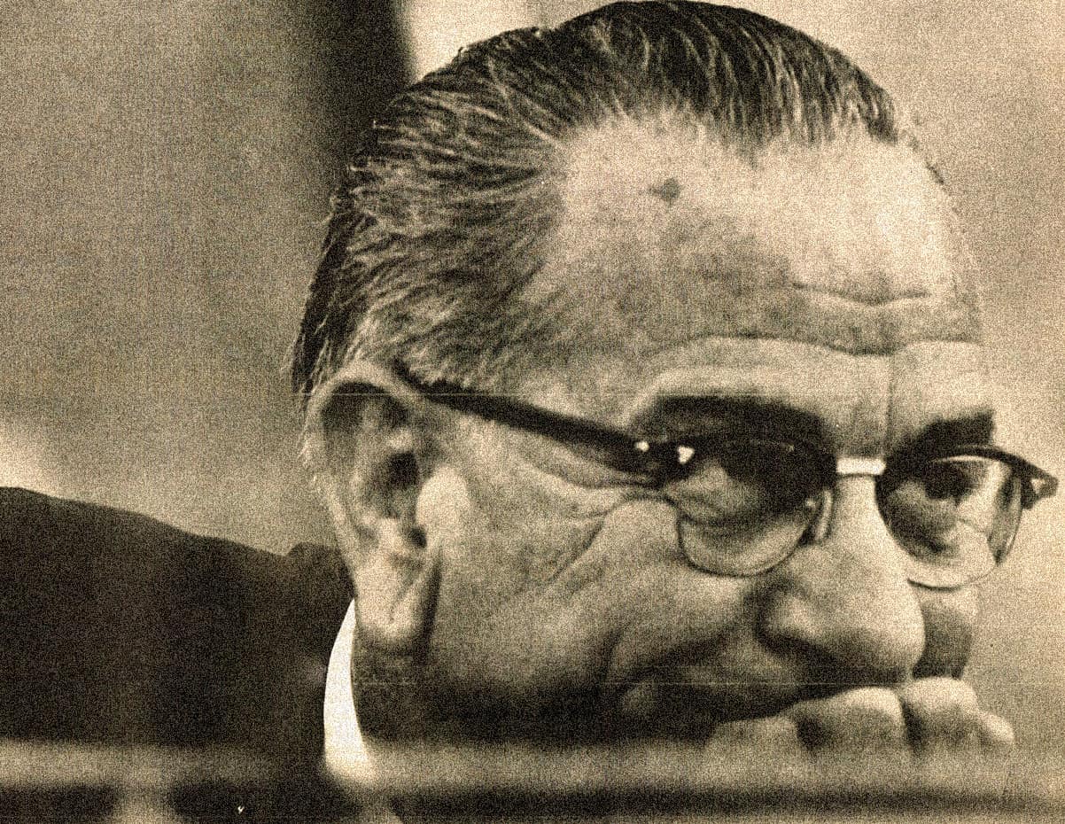 Old man with glasses resting his chin on his hand, black and white photograph, vintage portrait, historical figure, thoughtful expression, nostalgic image, classic photo, vintage photography, historical history, past daily archive.