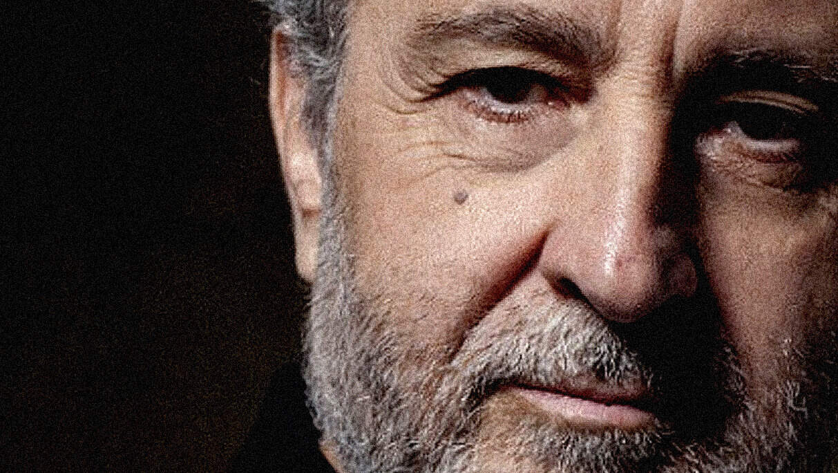 Close-up portrait of an older man with a gray beard and expressive eyes, highlighting themes of history, news, and music archive preservation.