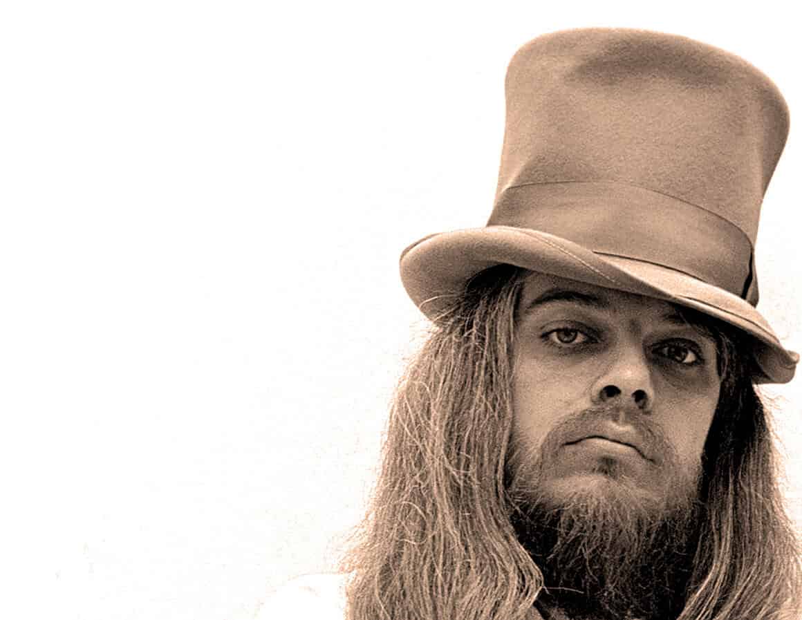 Vintage portrait of a man with long hair and beard wearing a tall hat, reminiscent of iconic 1960s or 1970s music and pop culture, highlighting historical and musical archive significance.