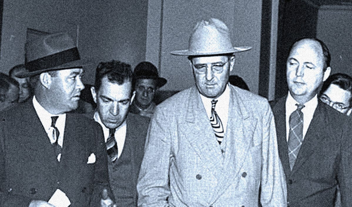 Vintage black and white photo of men in suits and hats at a historical event, reflecting 1950s fashion, illustrating mid-20th century news and history documentation.