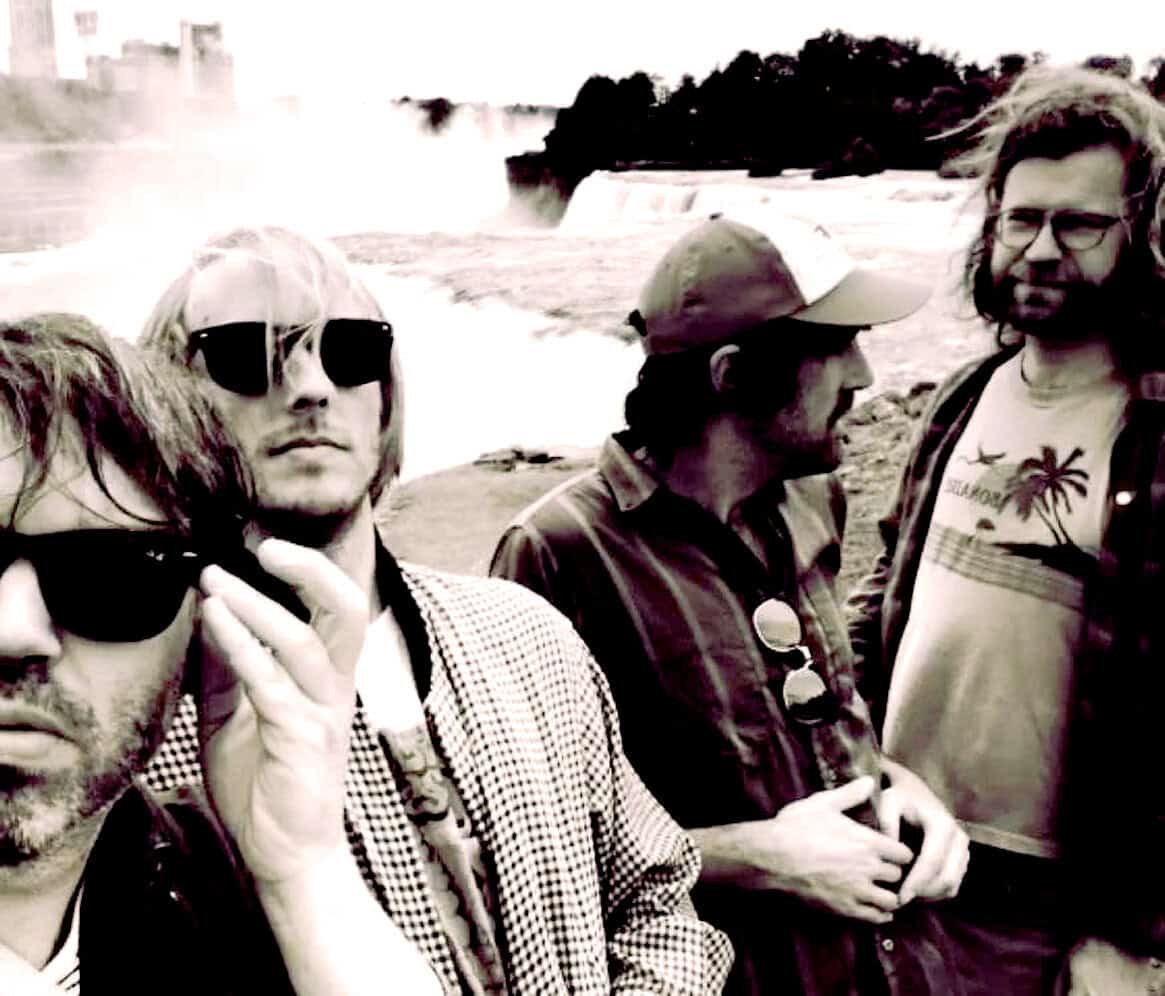 Cold War era photograph of four men standing near Niagara Falls, capturing historic moments in news and music history, emphasizing vintage style, authenticity, and iconic outdoor scenery.