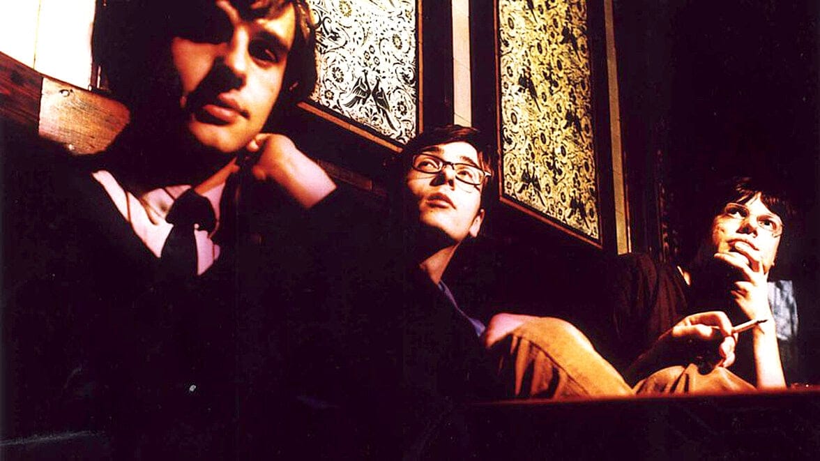 Teenagers sitting in a cozy vintage café, capturing a nostalgic atmosphere with artful lighting and patterned wallpaper, reflecting a cultural scene connected to music and news archives.