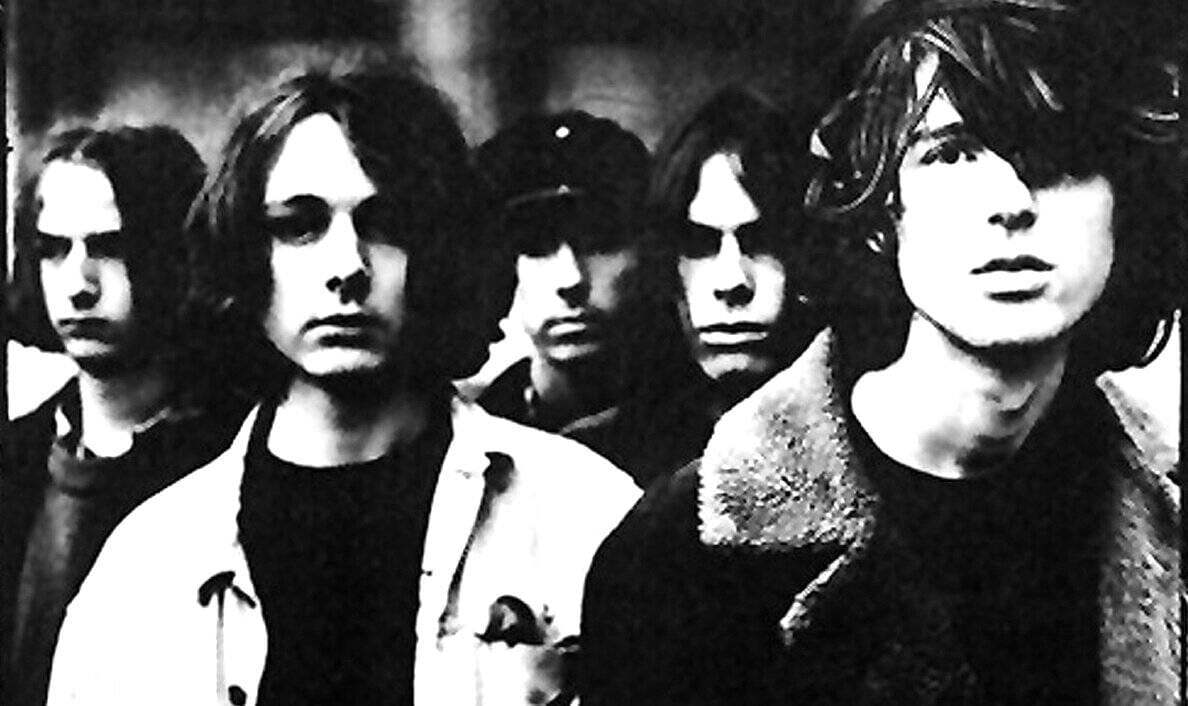 A black and white image of a punk rock band with four members, showcasing iconic hairstyles and fashion typical of the late 1970s punk movement. Perfect for music history and archive collections.