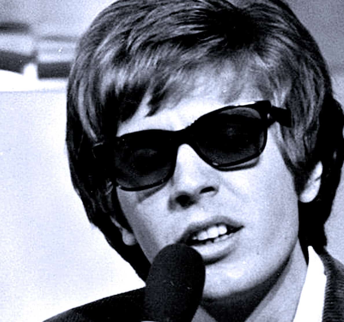 Vintage black and white photo of a female singer wearing sunglasses, speaking into a microphone, capturing historic music and pop culture moments.
