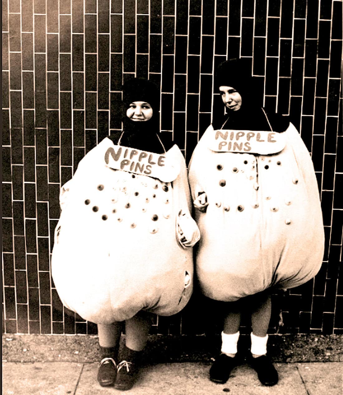 Nipple pins costume, women dressed as nipple pins for fun, vintage street fashion, humorous costume idea, quirky clothing style, creative Halloween outfit, street photography, retro black-and-white photo, playful costume design, pop culture costume.