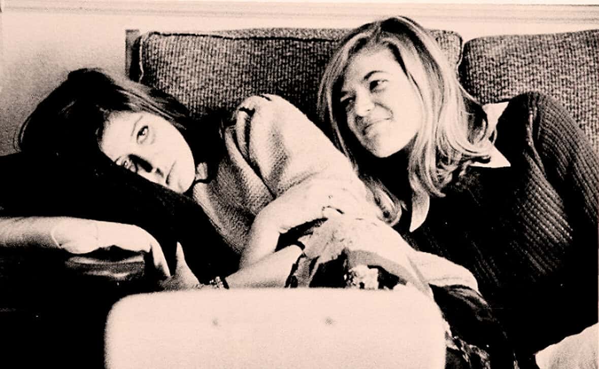 Photo of two women lying on a couch, sharing a moment together, capturing casual, candid moments and friendship, as featured in the Past Daily sound archive of news, history, and music.