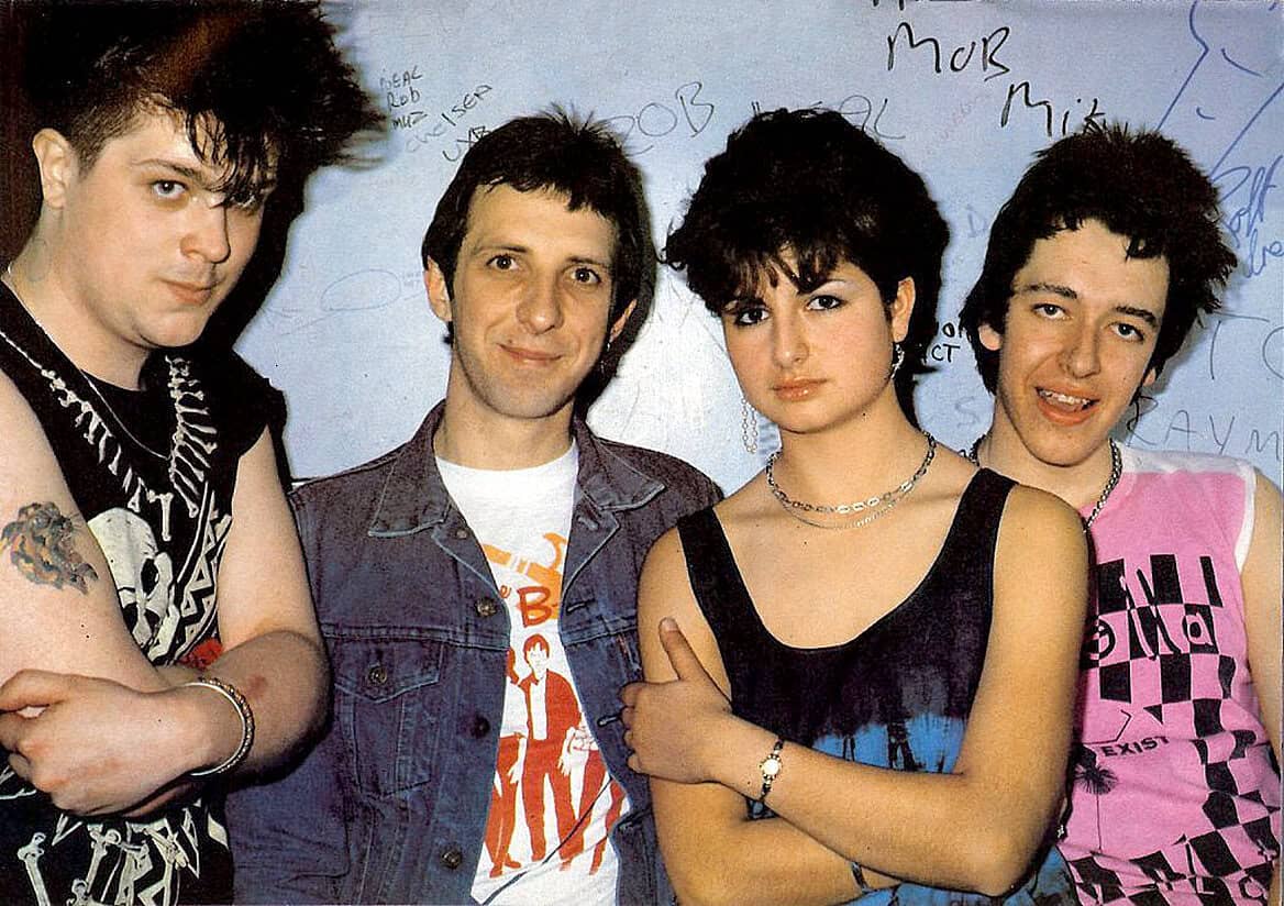 Vintage alternative rock band photo with members exhibiting 1980s punk and new wave style, capturing the music and cultural history of the late 20th century.