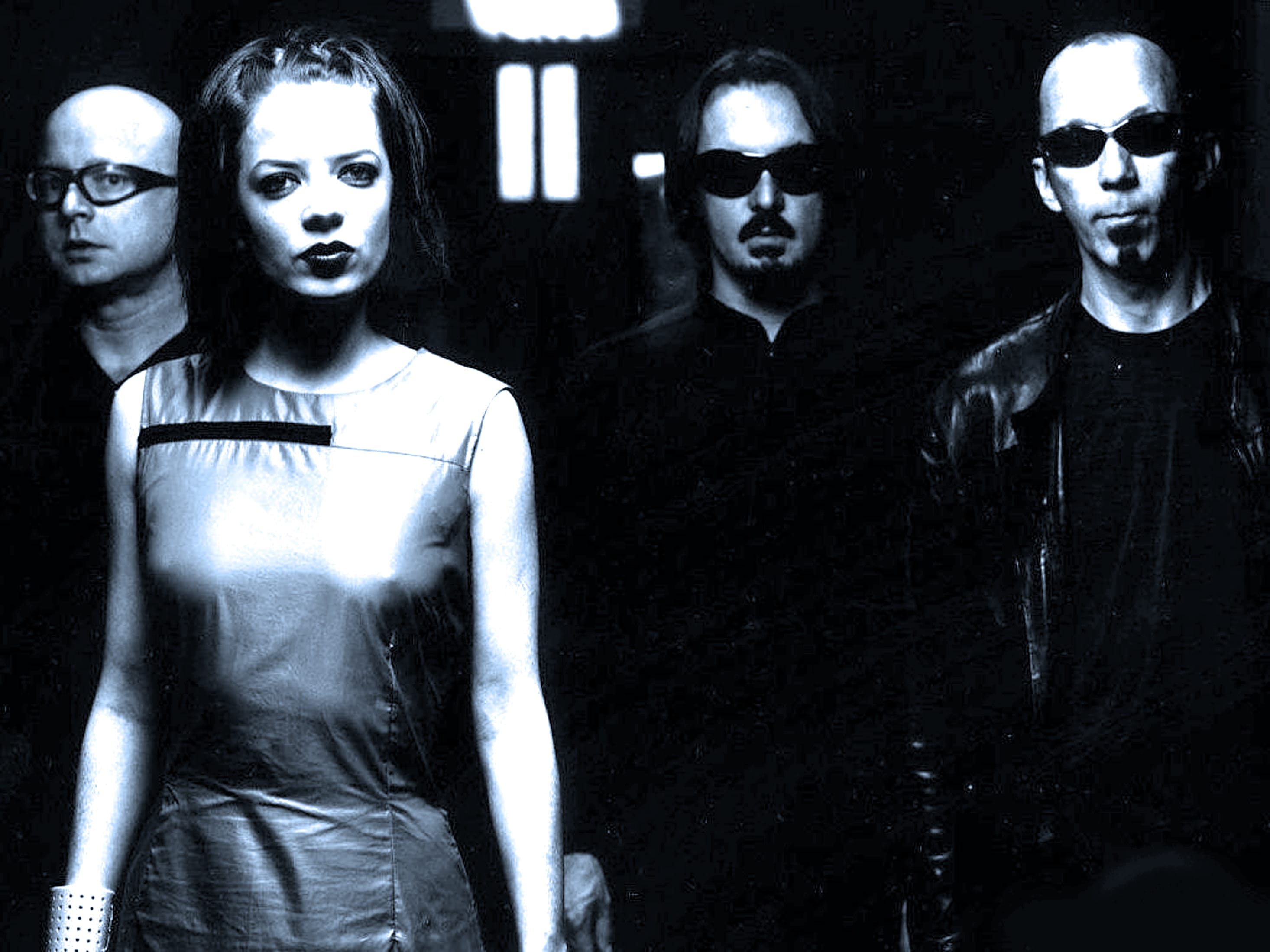 Futuristic band members with leather and sunglasses in a moody black-and-white image, highlighting music, news, and cultural history.