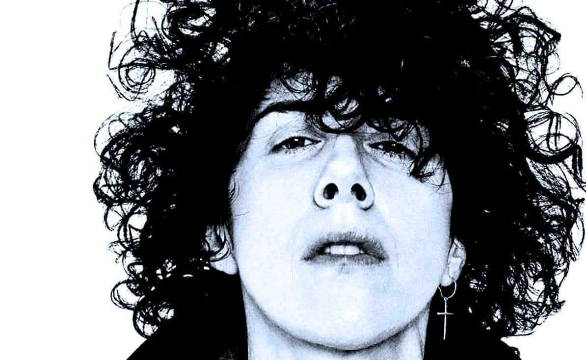 Portrait of a woman with curly black hair and cross earring, representing music history and archives.