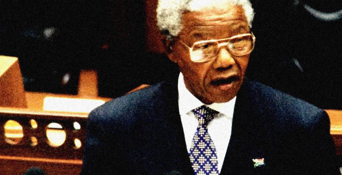 Elderly man with white hair and glasses speaking at a news event, symbolizing historical news reporting and influential speeches.