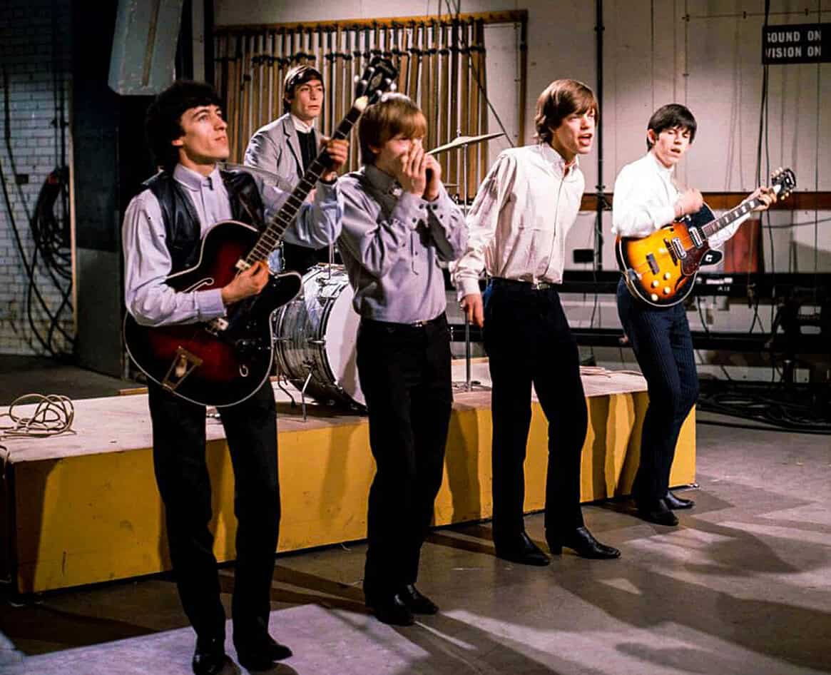 Retro band of young musicians performing on stage with guitars and drums, capturing the spirit of 1960s musical history and archive content.