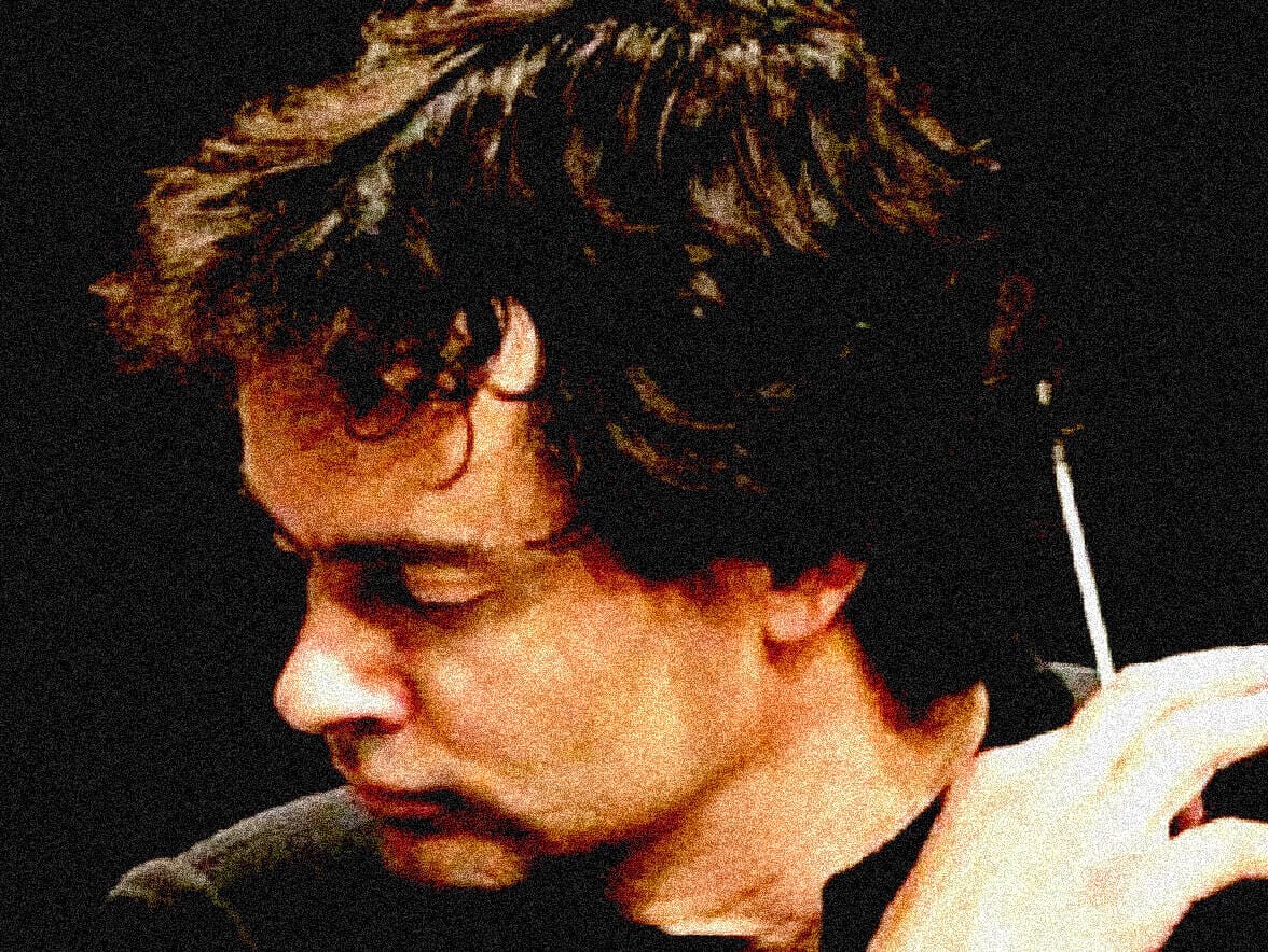 Close-up of a young man with dark, wavy hair, introspective expression, and wearing sunglasses, representing the nostalgic and historical essence of the Past Daily archive of news, history, and music.