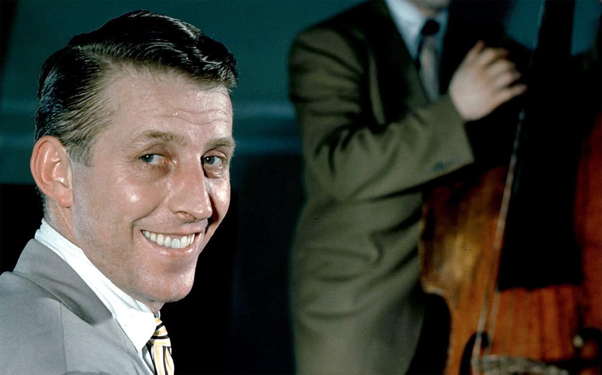 Gleaming man in classic suit smiling at the camera, vintage news and music archive background.