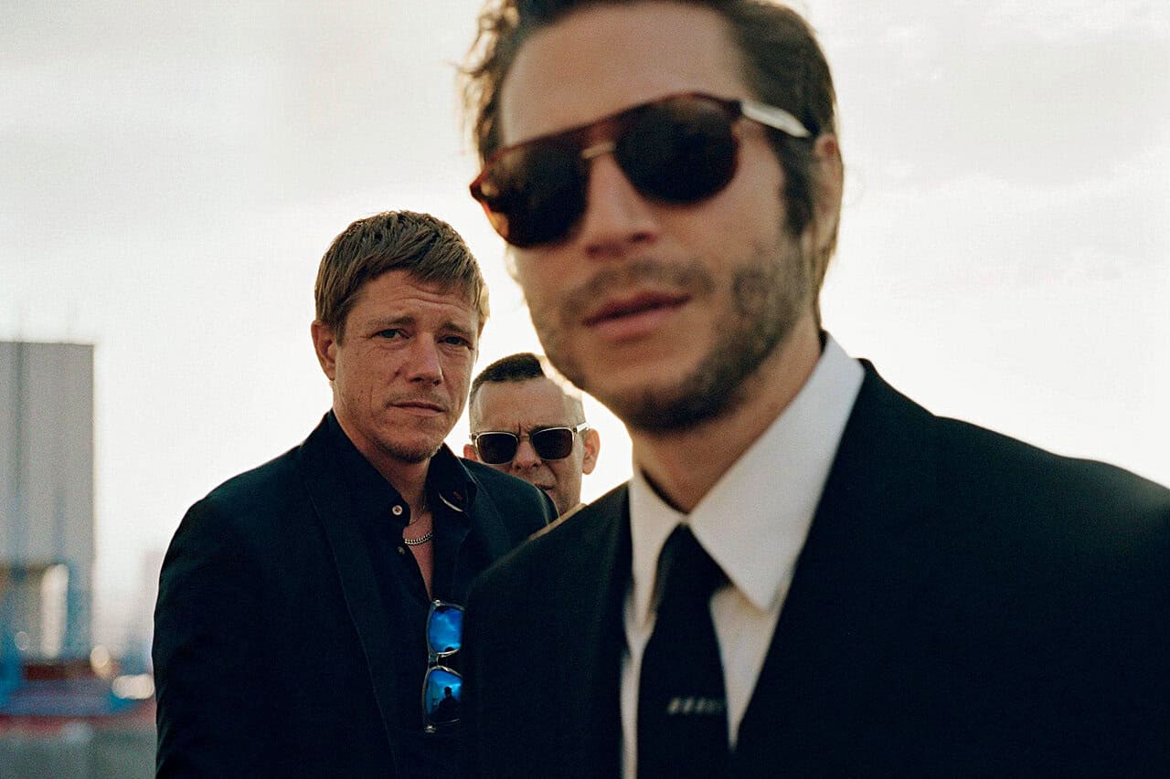 A scene from the film "Reservoir Dogs," featuring men in black suits and sunglasses, capturing classic crime drama imagery.