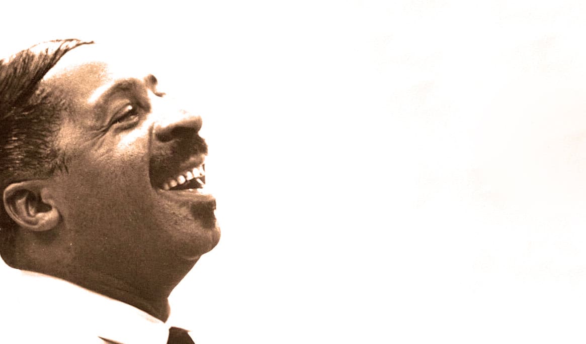 Vintage black and white photo of happy man laughing, symbolizing music, news, and historical archival content at Past Daily.