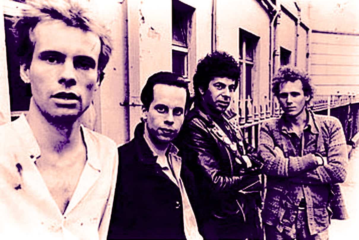 Black and white photo of The Clash, a legendary punk rock band, standing outdoors near a building, showcasing their distinctive style and rebellious attitude, iconic in music history.