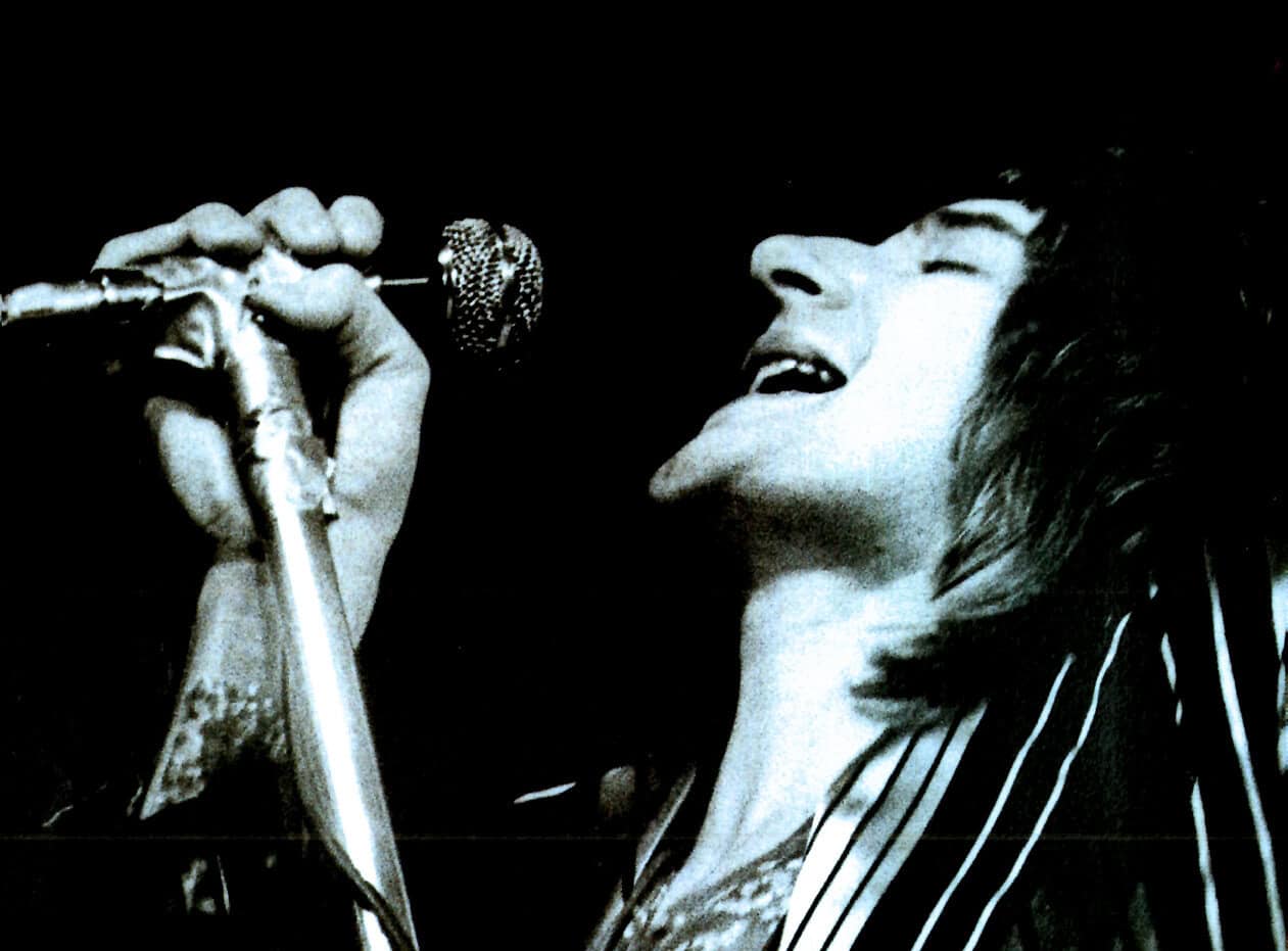 A black and white photo of a female singer passionately performing into a vintage microphone, capturing the essence of classic music and sound archives on Past Daily.