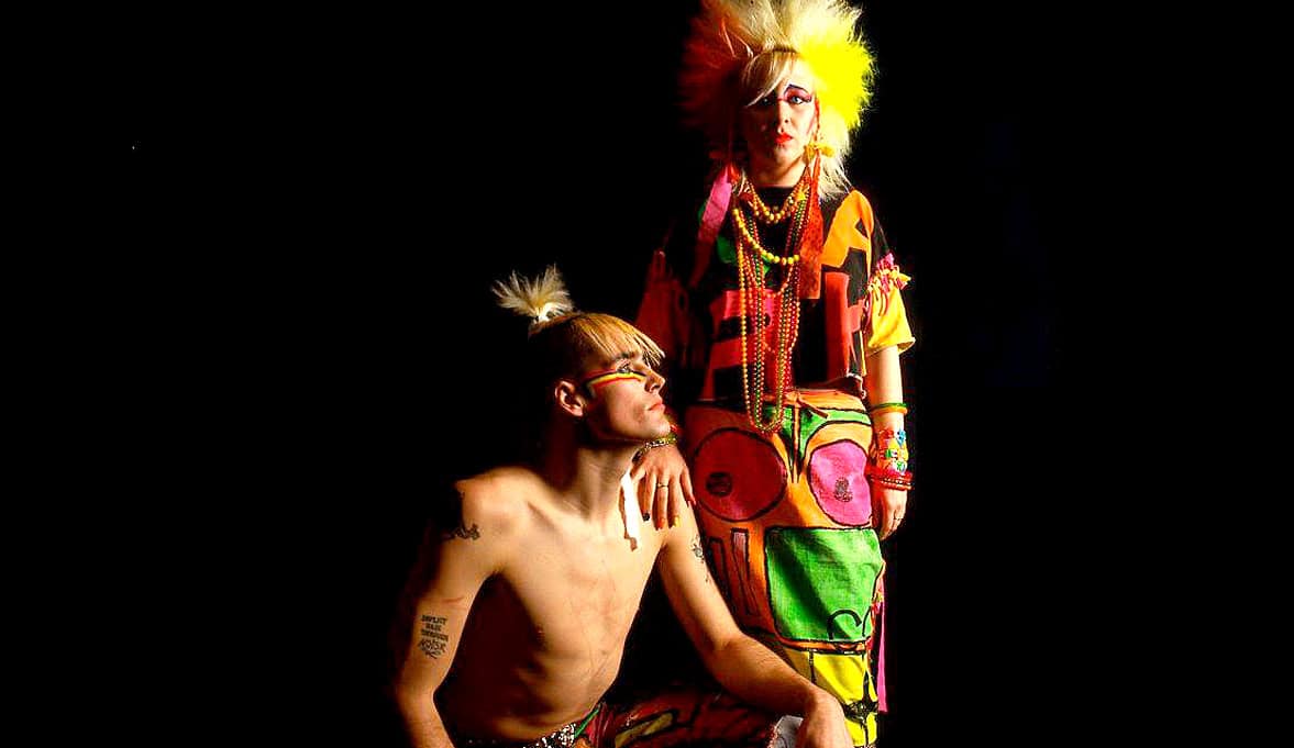 Colorful punk rock performers with vibrant outfits and bold hairstyles, highlighting music, music history, and alternative fashion. Perfect for a sound archive of music history and cultural expression.