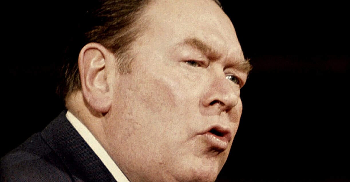 Close-up of a man with reddish hair and a serious expression, symbolizing news and historical reporting, for use in historical news archives and sound recordings.