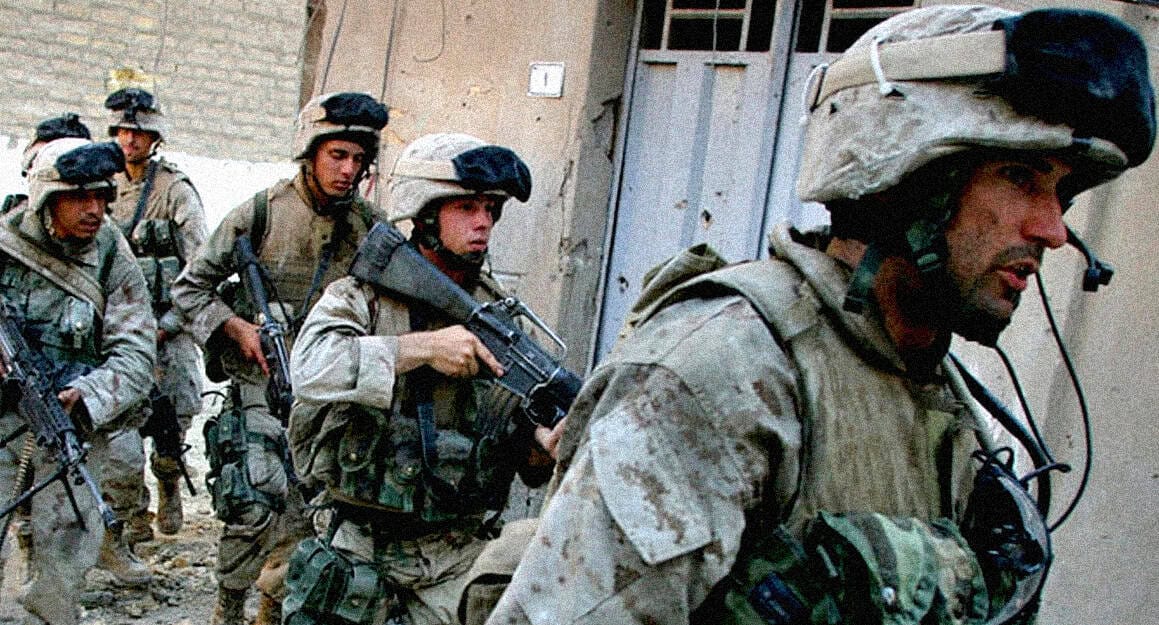 Armed soldiers in combat gear walking through an urban area with buildings in the background, representing military news, history, and conflict coverage for historical sound archives and news updates.